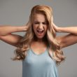 Portrait of young woman shouting with her eyes closed and covering her ears with hands